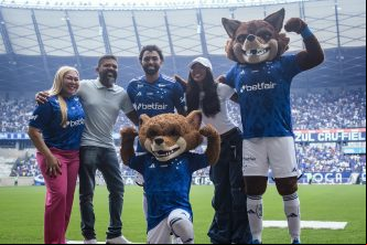 Grupo com torcedores e mascote em estádio de futebol